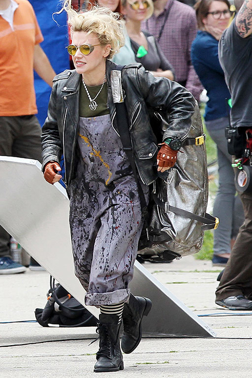 Kate McKinnon in Ghostbusters, wearing paint-stained dungarees, a leather jacket, driving gloves, big black boots and black & white striped socks.